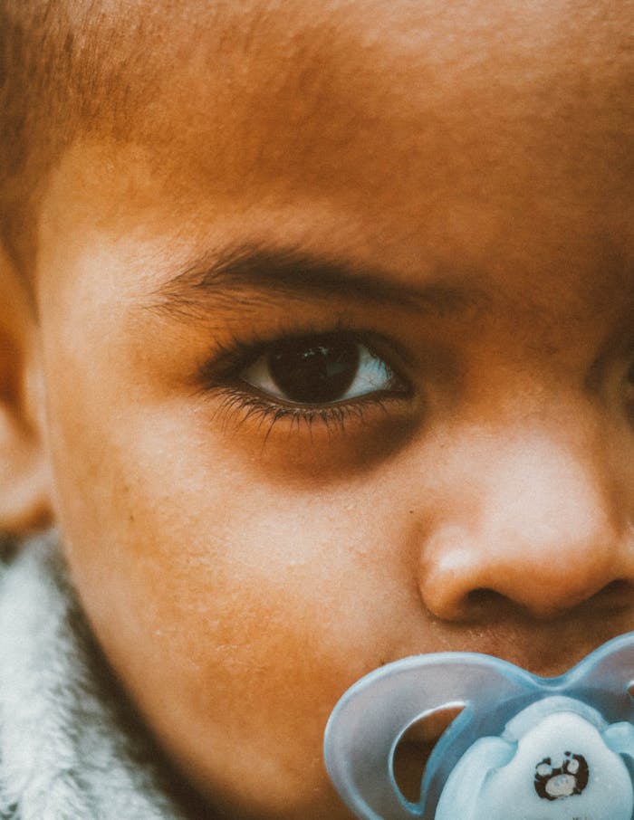 Heartfelt close-up of a child's face with a pacifier, capturing innocence and pensive expression.
