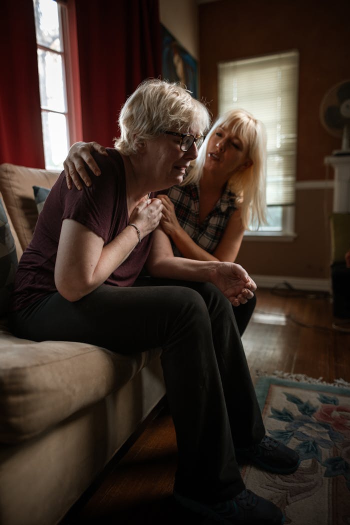 Two adults sharing a moment of emotional support on the couch indoors.