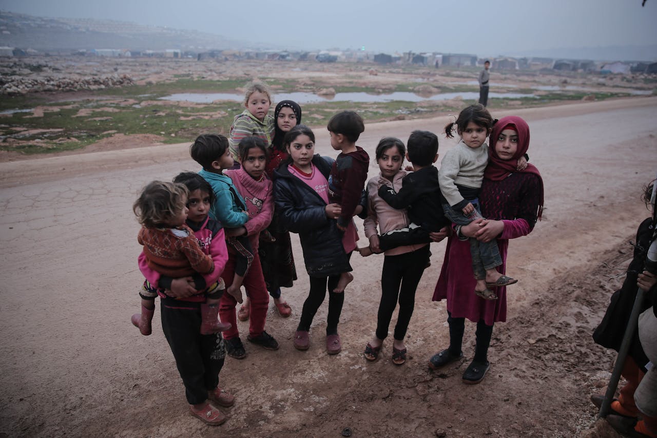 A group of children standing on an unpaved road in Idlib, Syria, showcasing resilience.